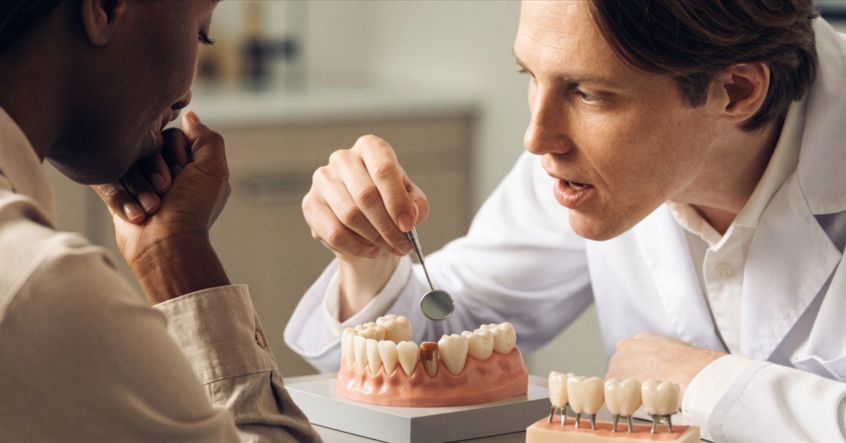 Dentist evaluating restored neighboring teeth before planning a dental bridge