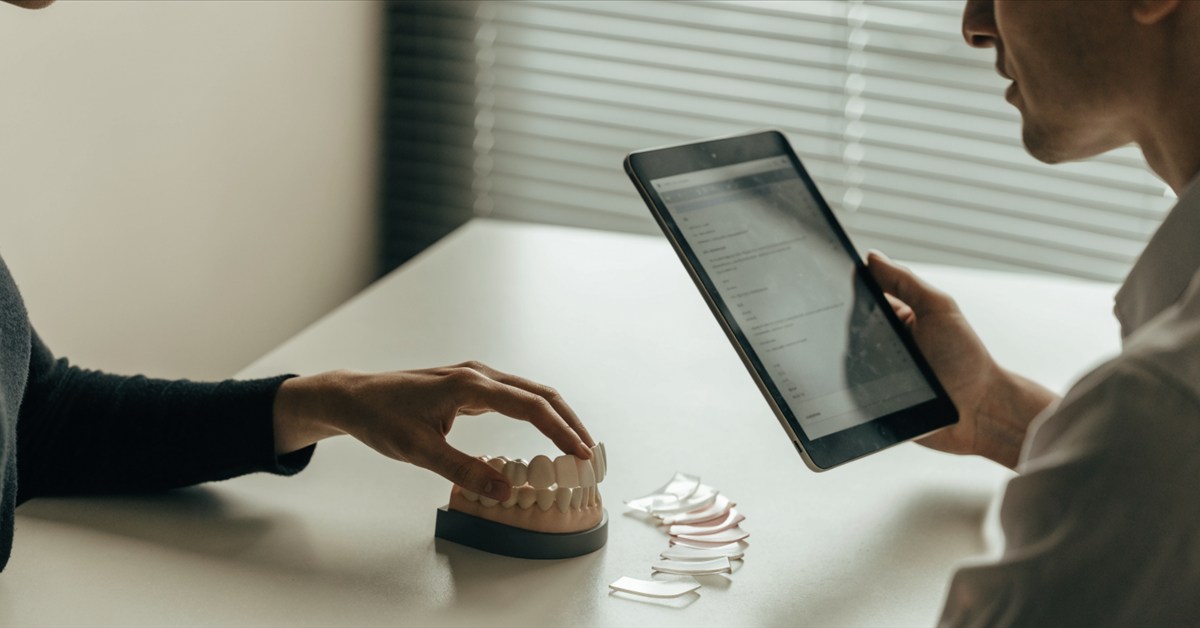 Dentist and patient reviewing a personalized E-max veneer treatment plan and ceramic samples