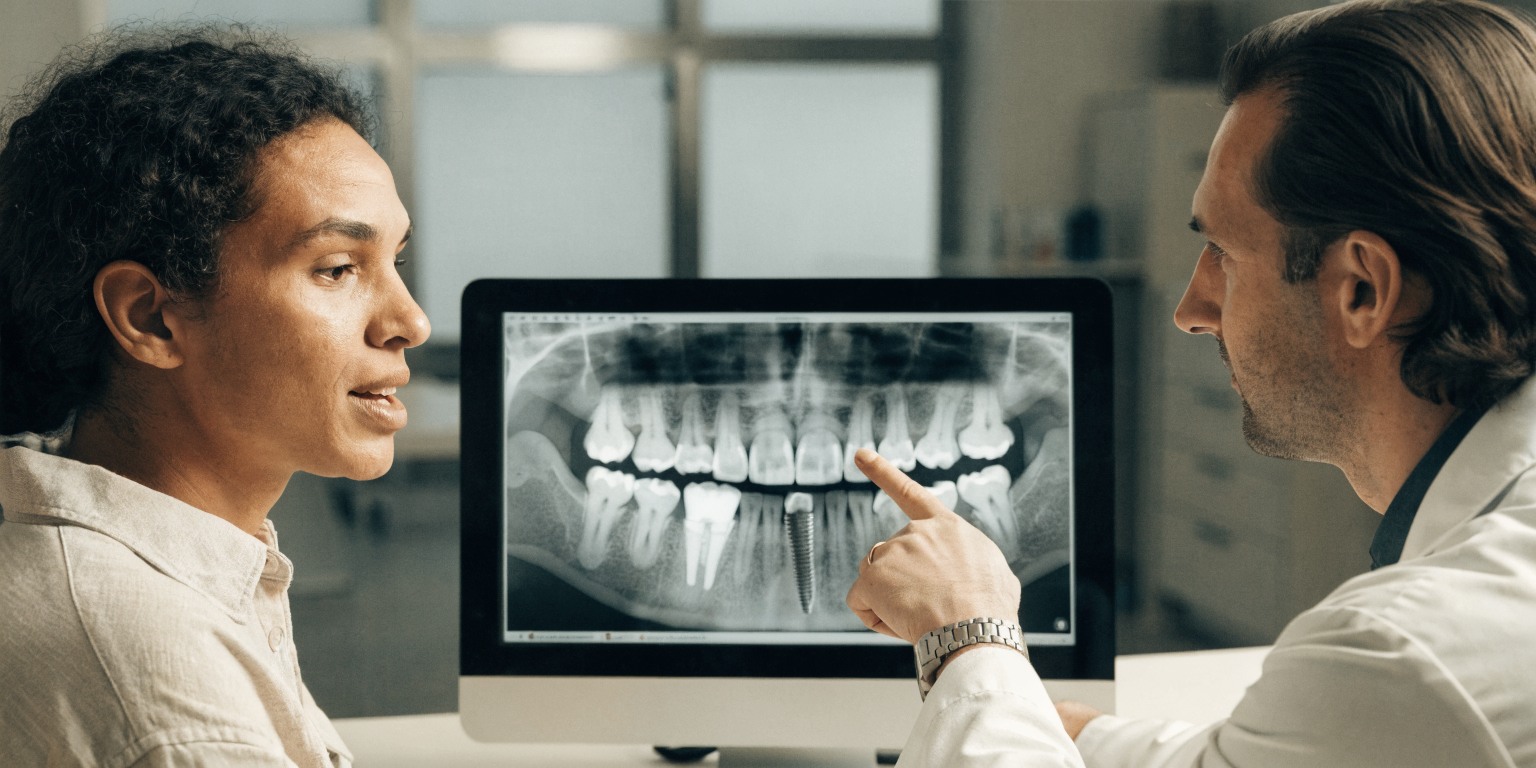 Dentist reviewing dental implant imaging and risk factors with an adult patient