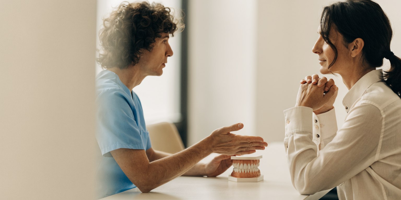 Dentist and patient discussing a full-arch dental bridge using a teaching model