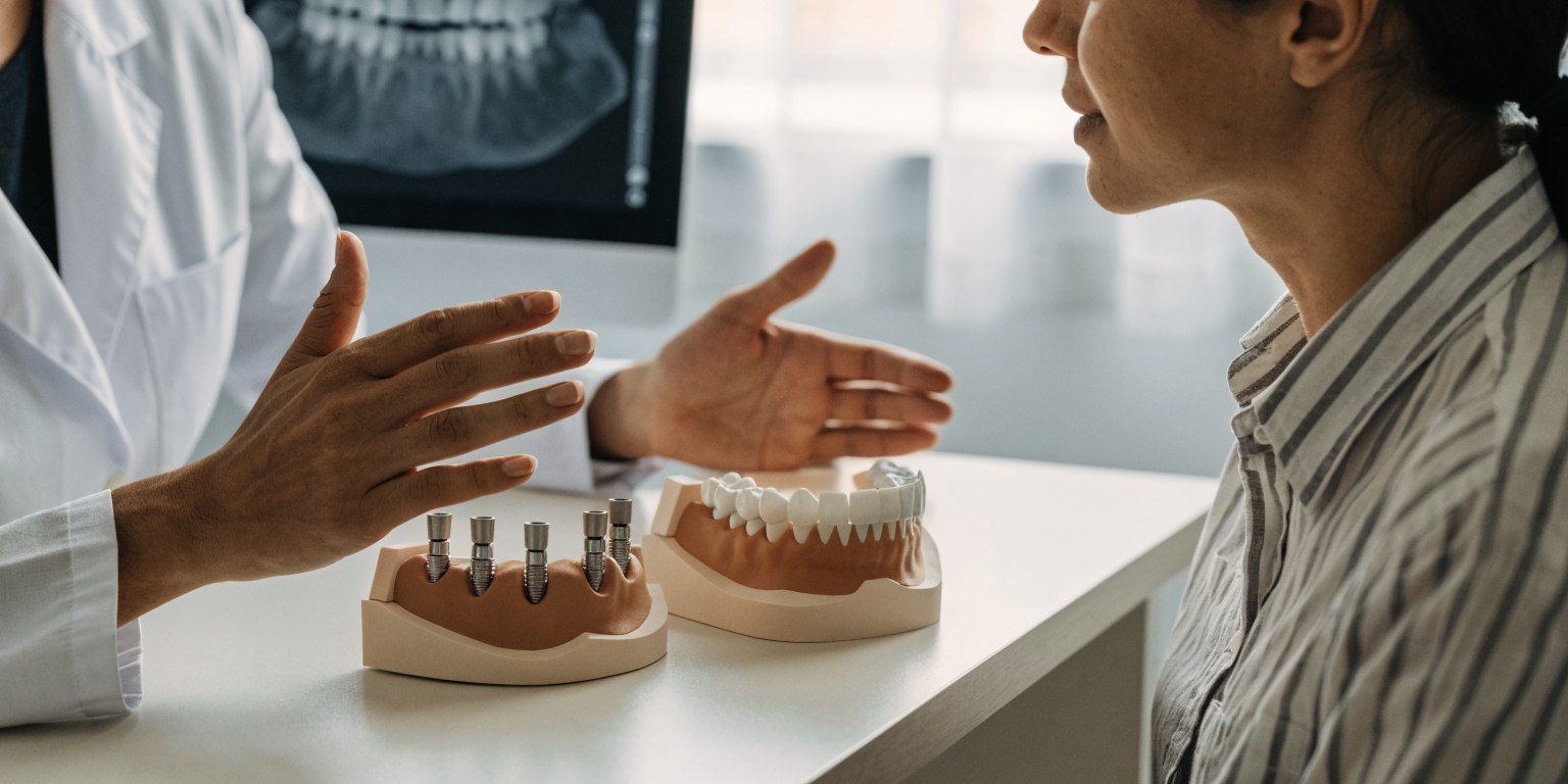 Implant clinician reviewing a full-arch implant treatment plan with a patient using jaw models