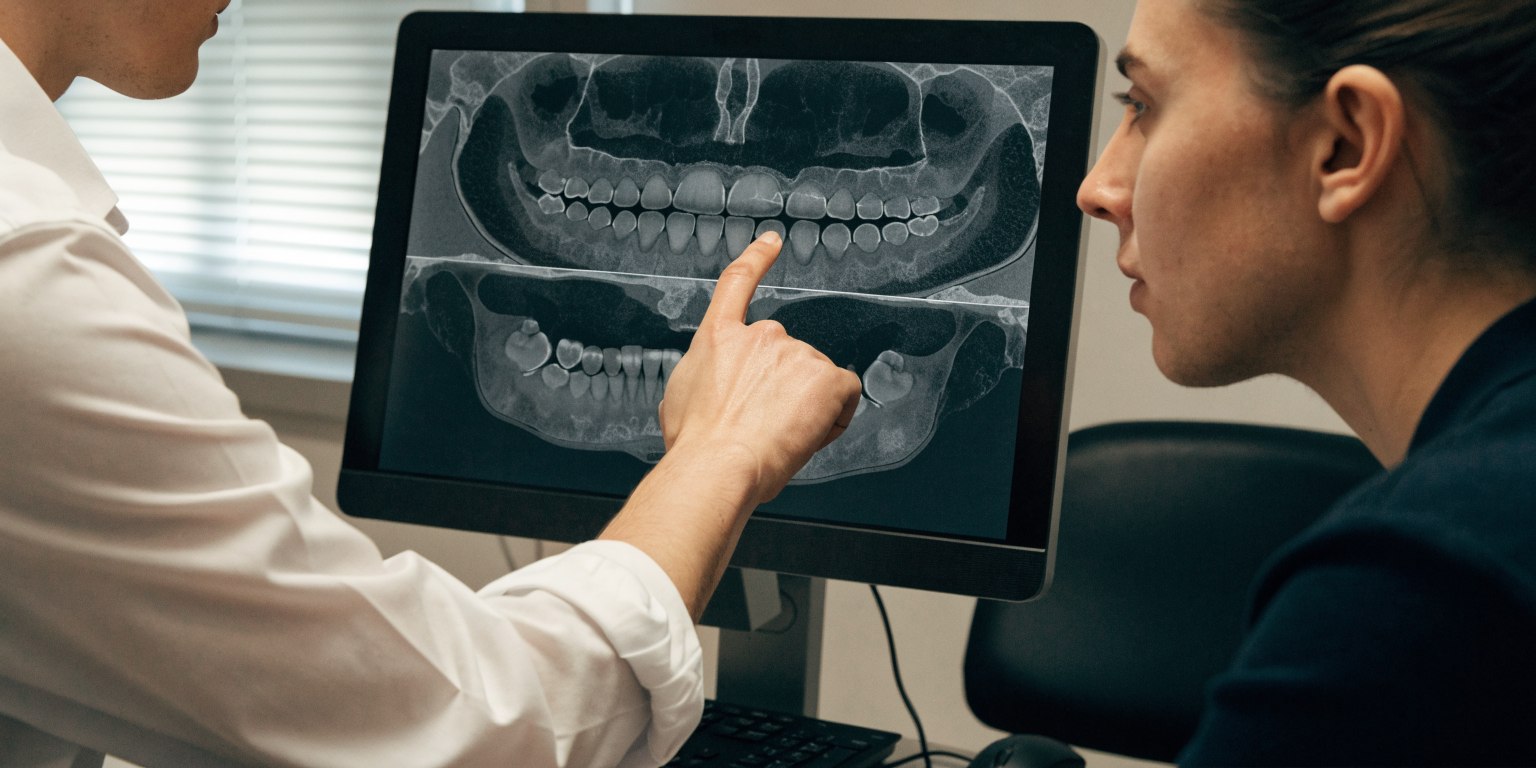 Dentist assessing jawbone dimensions on CBCT imaging for dental implant planning
