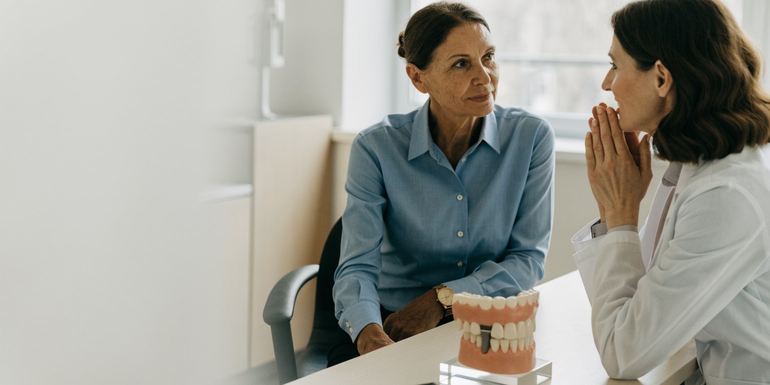 Adult patient discussing long-term dental implant care with a dentist