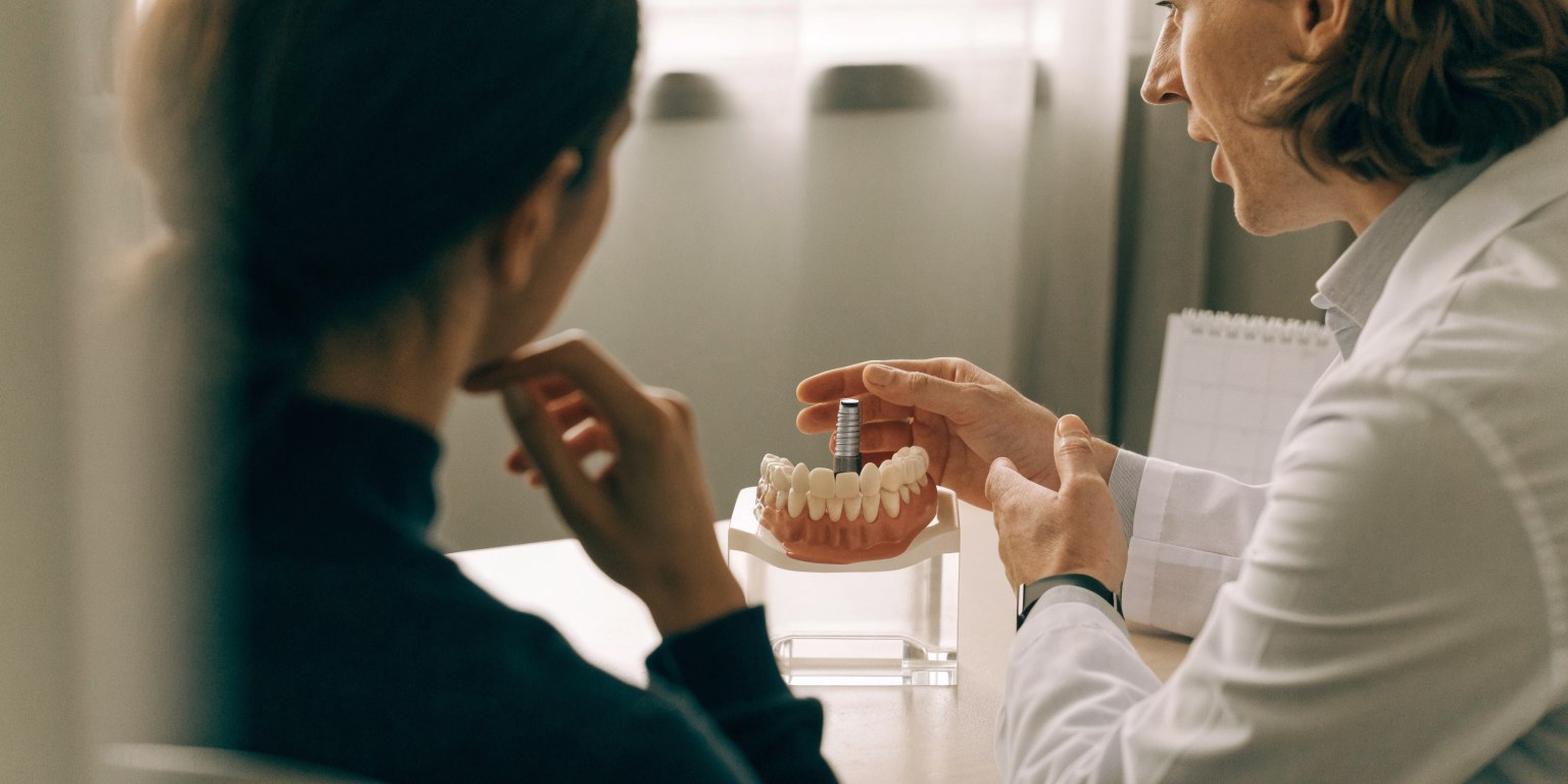 A dentist discusses the stages and timing of implant treatment with a patient
