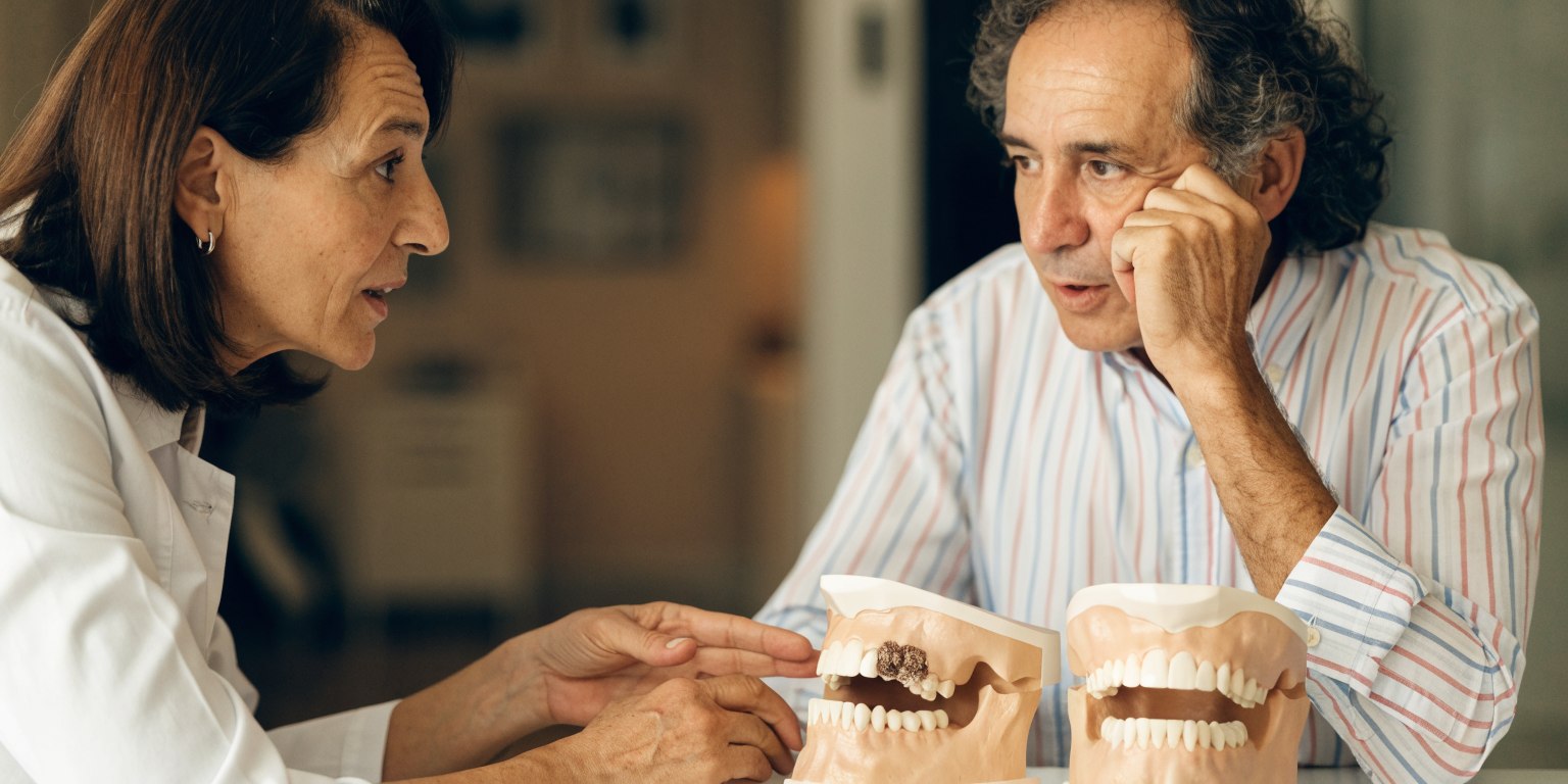 Dentist explaining open and closed sinus lift approaches with dental models
