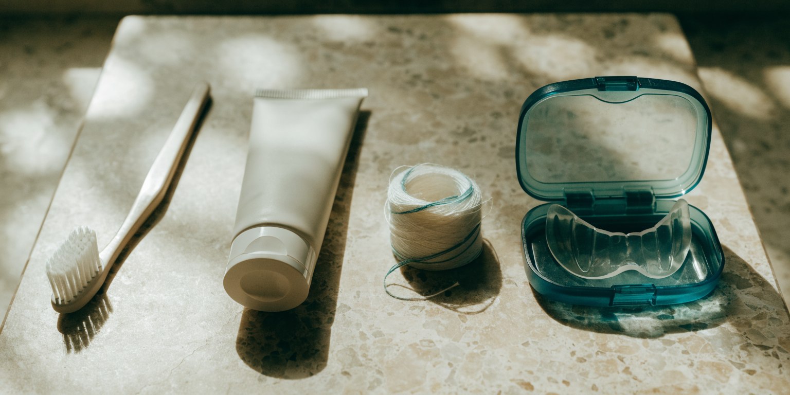 Toothbrush, floss and a dental night guard arranged for home care