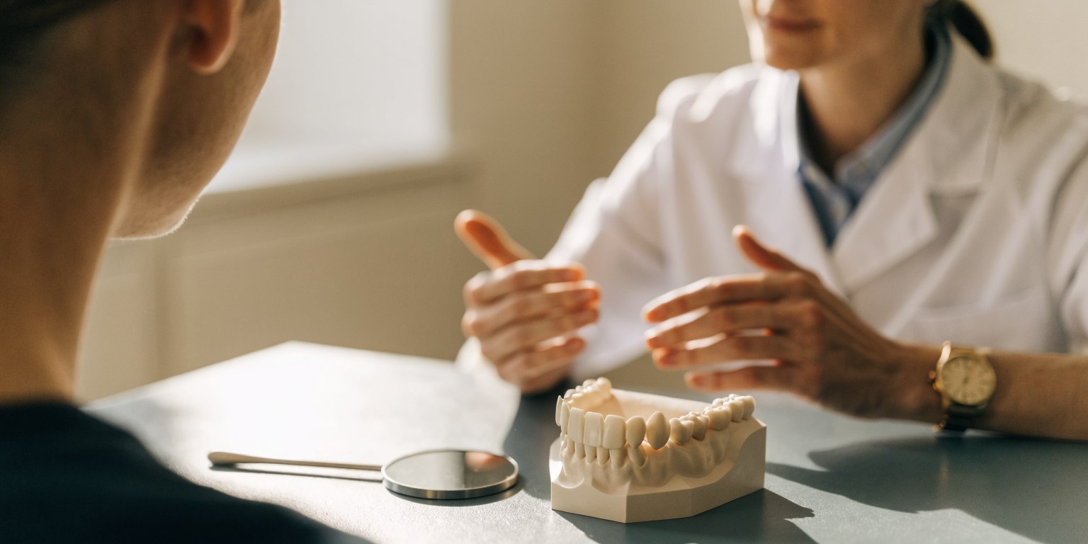 Dentist and patient reviewing treatment options with a model and mirror