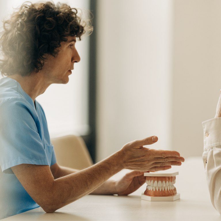 Dentist and patient discussing a full-arch dental bridge using a teaching model