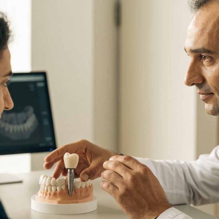 Dentist explaining a single dental implant treatment plan to a patient with an implant model