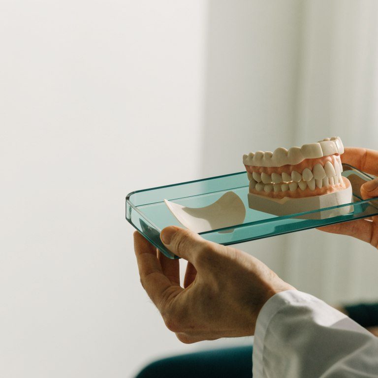 Dentist explaining a ceramic veneer sample and dental model to a patient
