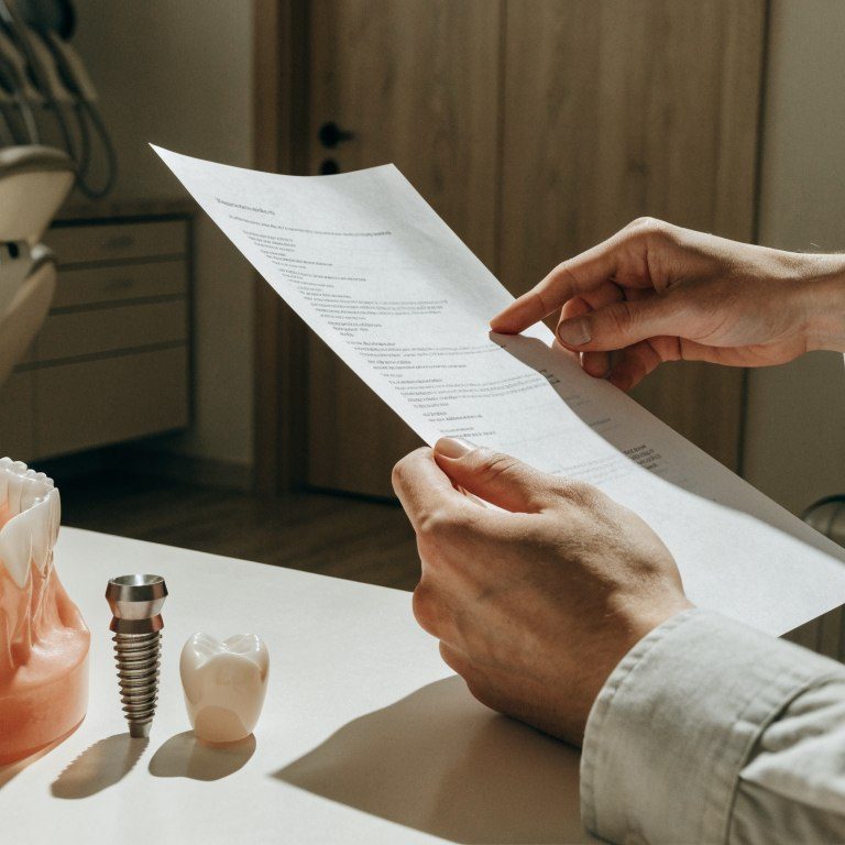 A patient reviews dental implant components and a treatment estimate with a dentist