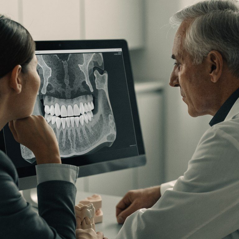 Dentist reviewing a 3D jaw scan with a patient while discussing dental implant options for bone loss