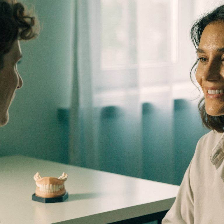 Patient and dentist discussing ongoing care beside a dental model